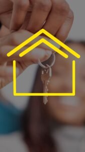 Close-up of hands holding house keys with yellow house icon overlay, representing real estate.